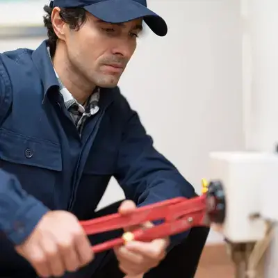 Technician in blue uniform using a wrench to adjust a gas or water meter indoors.
